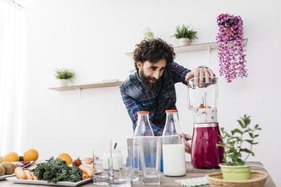 Young man standing by glass at home