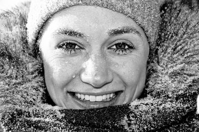 Close-up portrait of young woman in warm clothing with snow