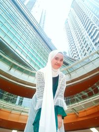 Portrait of woman standing against buildings in city