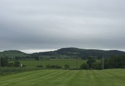 Scenic view of grassy field against cloudy sky