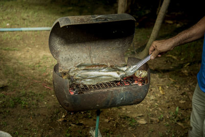 Close-up of man preparing food on barbecue grill