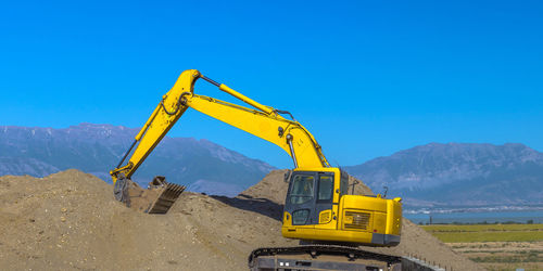 Crane at construction site against clear blue sky