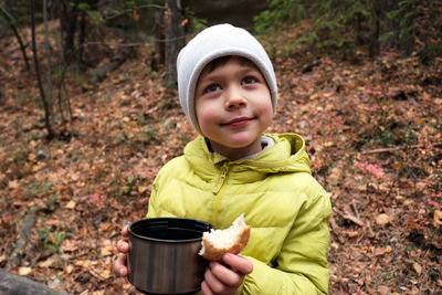 Boy with hot drink in forest
