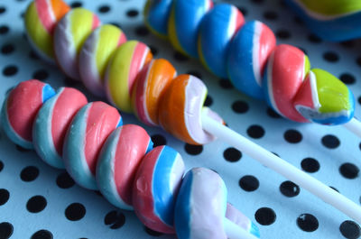 Twisted hard candy lollypops with stripes of pink, blue, yellow, white, dot pattern background