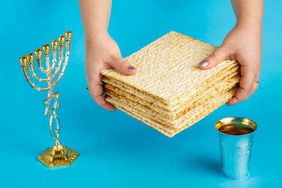 Low angle view of hand holding glass on table against blue background