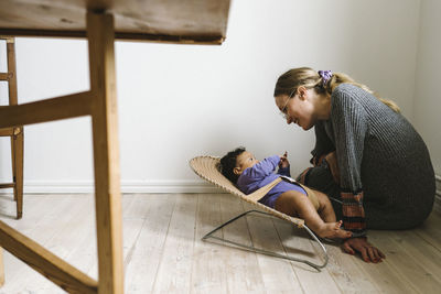 Mother looking at baby lying in bouncer