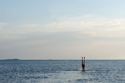 Man diving in sea against sky