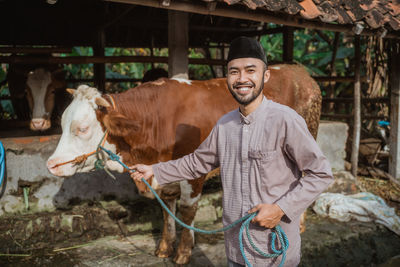 Portrait of smiling young man standing in pen