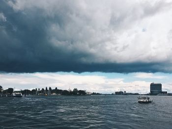 Boats sailing in sea against cloudy sky