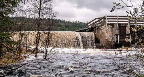 Built structure by bare trees against sky