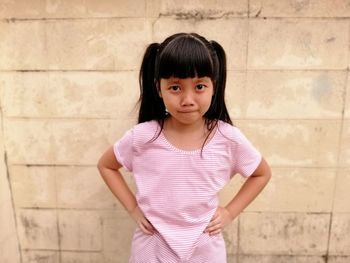 Portrait of girl standing against wall