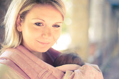 Portrait of smiling woman carrying baby girl outdoors