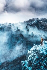 Man standing on snowcapped mountain against sky