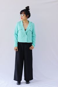 Young woman looking away while standing against white background