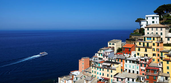 High angle view of residential buildings by sea against blue sky