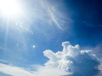 Low angle view of sunlight streaming through clouds