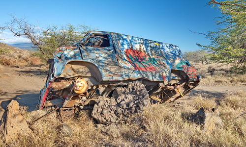 Graffiti on abandoned car against sky