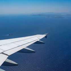 Airplane flying over sea against blue sky