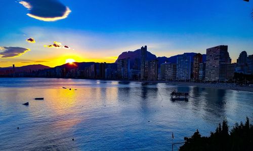 Scenic view of sea and buildings against sky at sunset