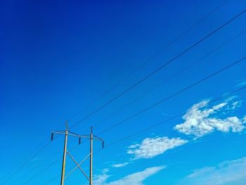 Low angle view of electricity pylon against blue sky