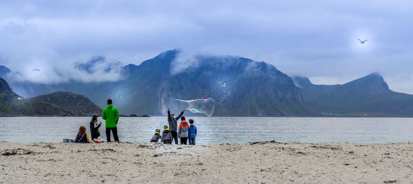 People on beach against mountains