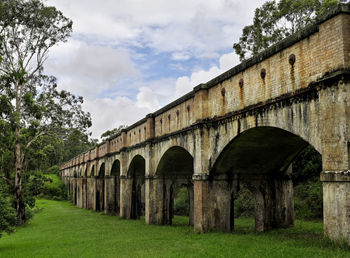 Historic aqueduct on field against sky