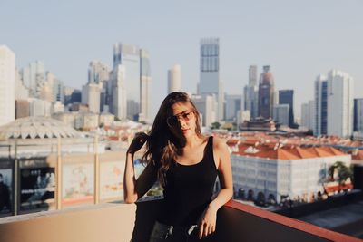 Young woman standing against cityscape