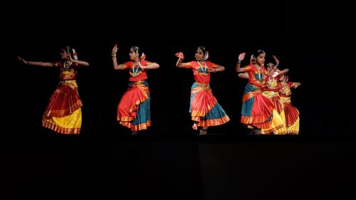 Group of people dancing against black background