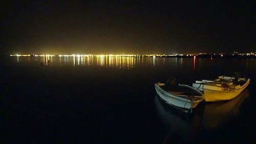 Boats moored in calm lake at night
