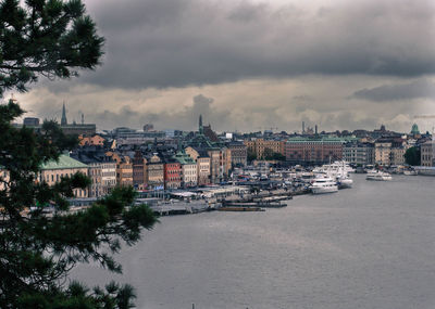 City at waterfront against cloudy sky