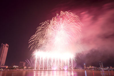 Low angle view of firework display over river at night