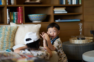 Portrait of cute boy by sibling at home