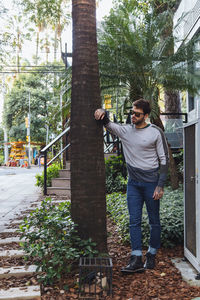 Young man standing by tree against plants