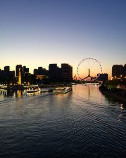 River and buildings in city against clear sky