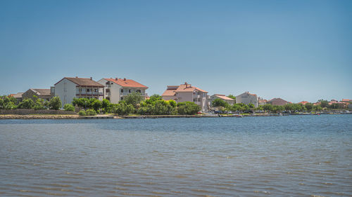 River by buildings against clear blue sky