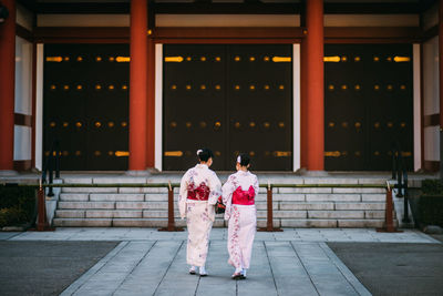 Rear view of women walking in front of temple