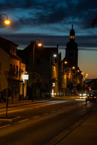 Illuminated street amidst buildings at night