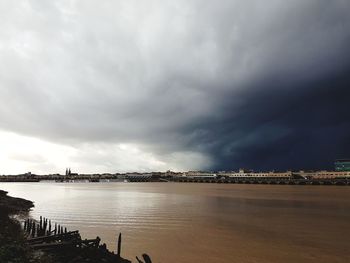 View of city by sea against storm clouds