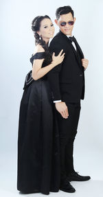 Side view of couple in wedding dress standing against gray background