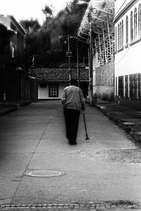Rear view of man walking on street against buildings