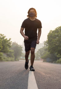 Full length of young man running on road sky