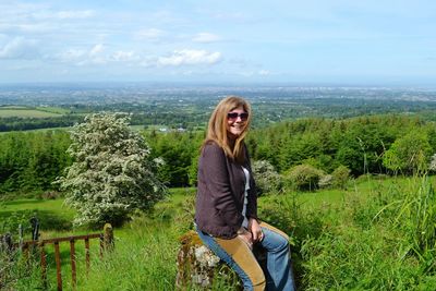 Portrait of young woman in sunglasses against trees on landscape