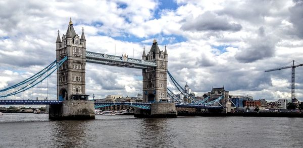 Tower bridge over thames river against cloudy sky