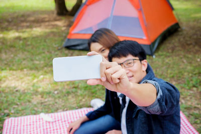 Happy boy photographing with mobile phone in grass