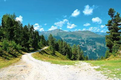 Road amidst trees and mountains against sky