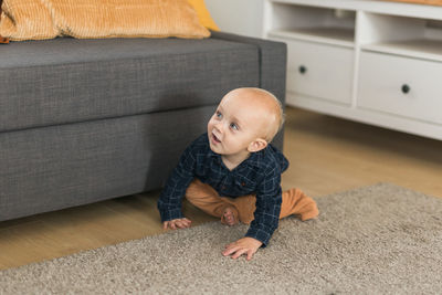 Cute boy sitting on sofa at home