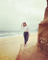 Woman standing on beach against sky