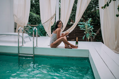 Portrait of woman sitting on swimming pool