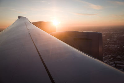 Airplane wing against sky during sunset