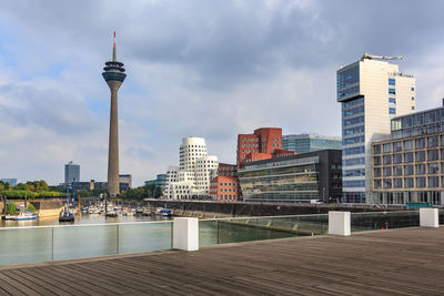 Modern buildings in city against cloudy sky